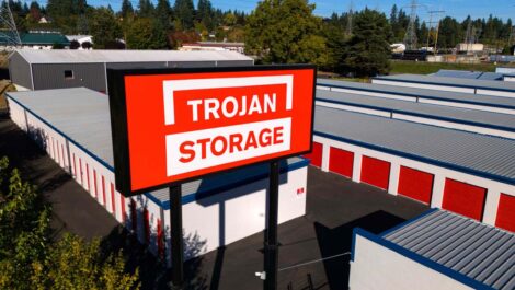 Trojan Storage sign above rows of outdoor storage units.