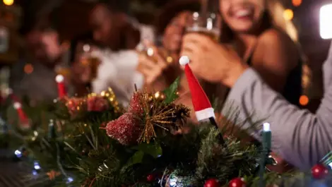 A group of people sitting at a decorated table enjoying a holiday party.