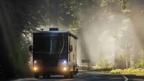 An RV traveling through beautiful wooded scenery.