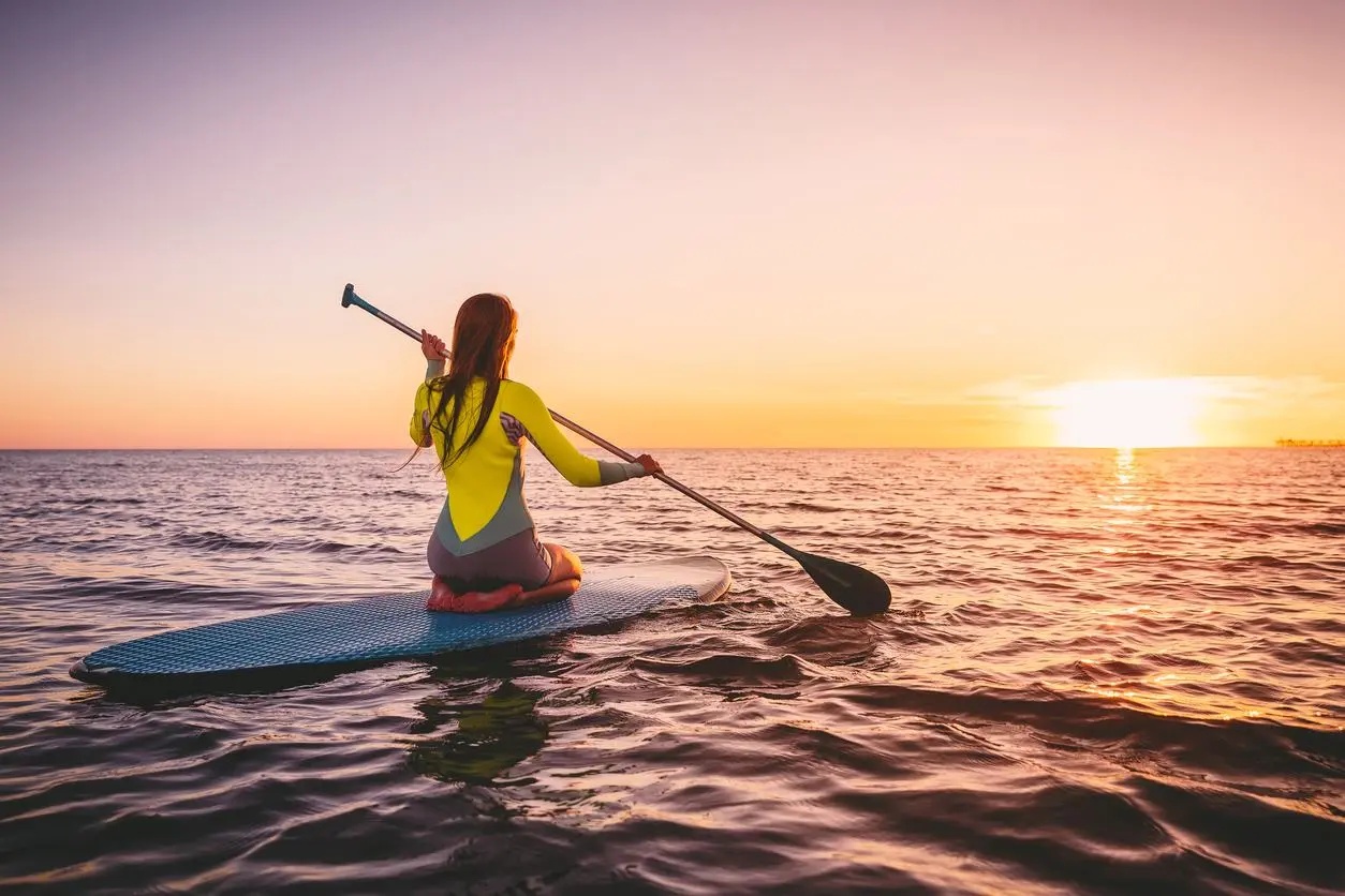 Young woman riding on a paddleboard on the shores of California.