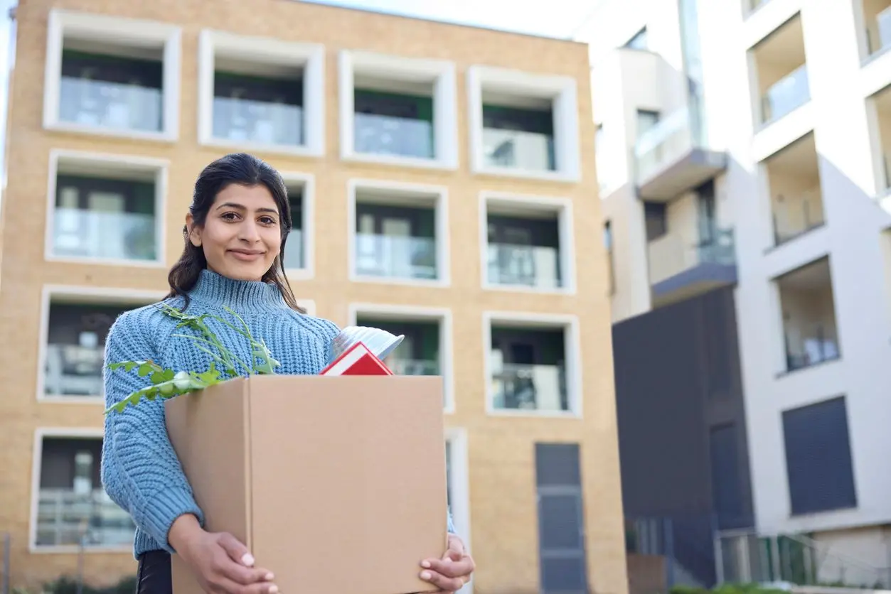 Young female student carrying items to her dorm room. 