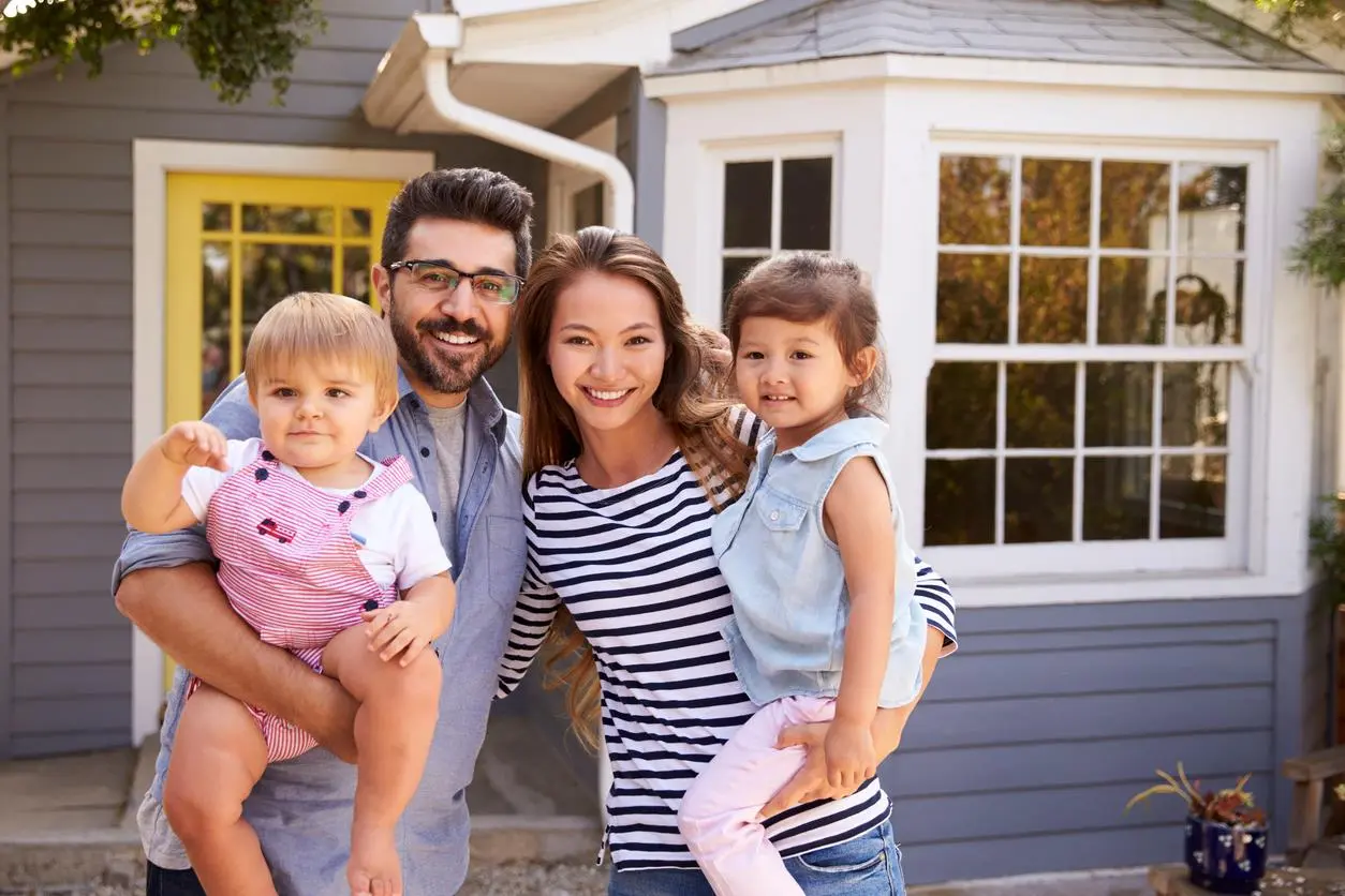 An excited young family standing in front of their new home.