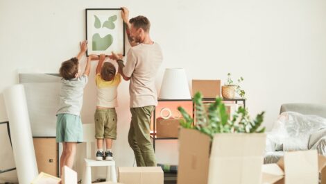 A father and his sons hanging a picture in their new home.