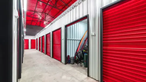 Corridor of self storage unit with red doors with camping gear